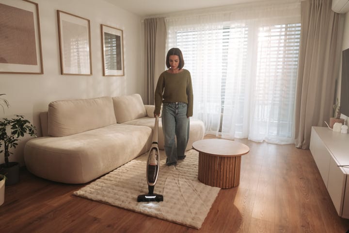 Woman Vacuuming Modern Living Room Carpet With Cordless Cleaner