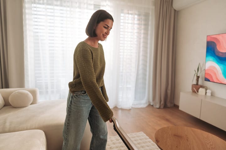 A Young Woman Happily Vacuums Her Modern Living Room Floor