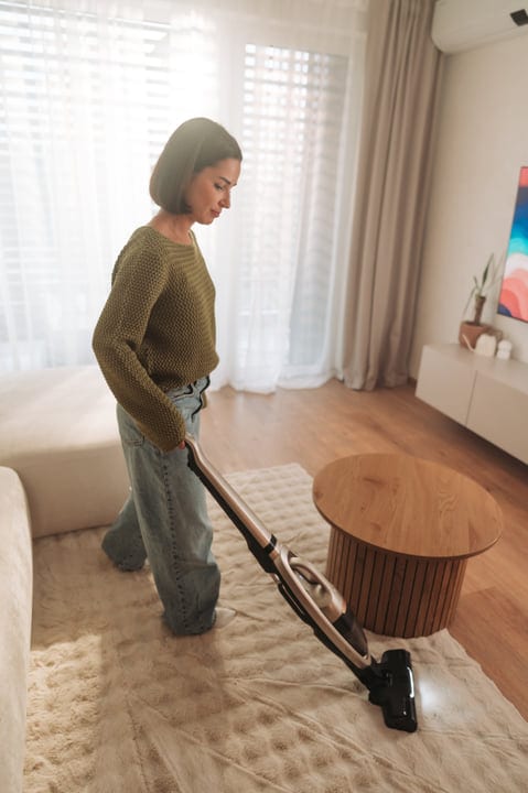 Woman Cleans Living Room Carpet With Cordless Vacuum Cleaner