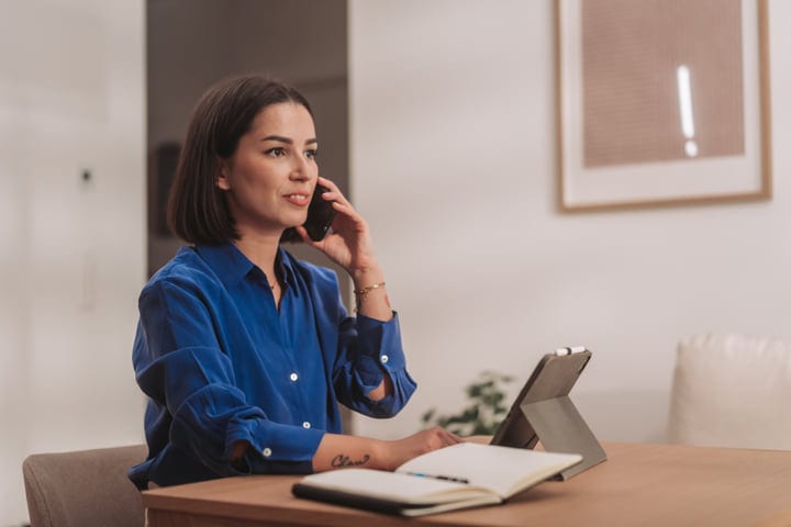 Young Woman Talking On Phone At Her Home Office Desk