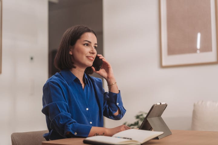 Young Woman Talking On Phone While Working At Home Desk