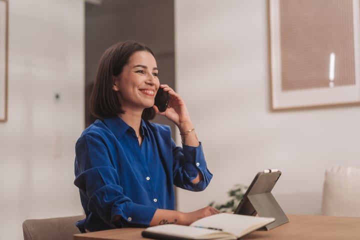 Smiling Woman Talking On Smartphone While Working At Home Office Desk