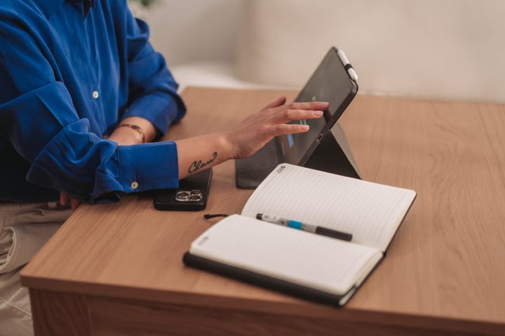 Woman Interacting With Digital Tablet And Notebook At Modern Wooden Desk