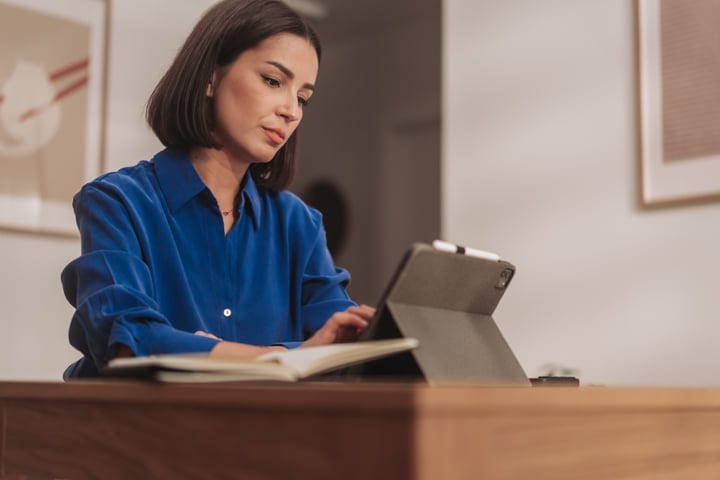 Focused Woman Engaged With Digital Tablet And Planner Indoors
