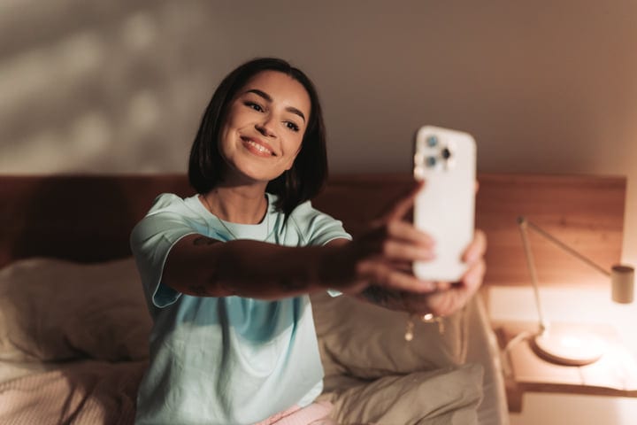 Smiling Woman Taking A Selfie With Smartphone In Her Bedroom
