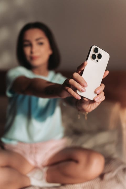 Woman Holding Smartphone Capturing Morning Routine In Bedroom At Home