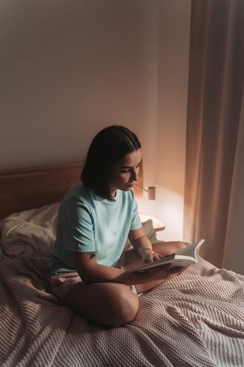 Young Woman Reads A Book In Bed During A Quiet Morning