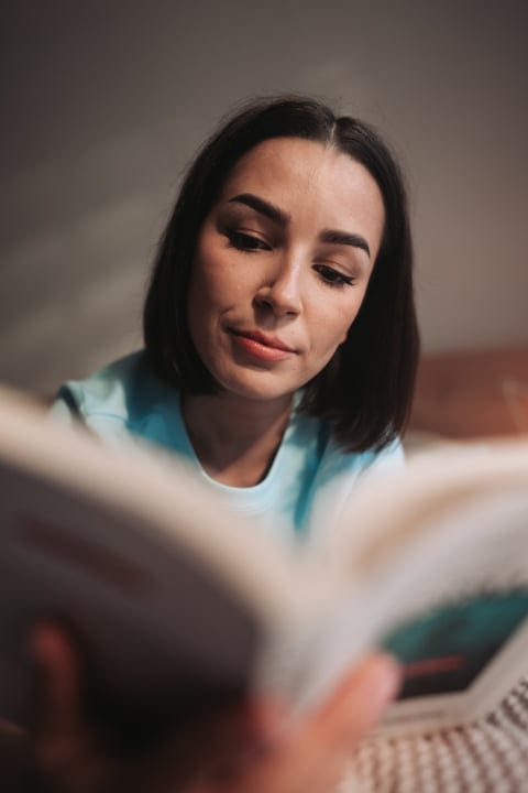 Young European Woman Reading A Book Indoors During Morning Light