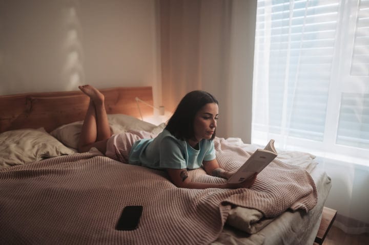 Woman Enjoys Quiet Morning Reading Book In Her Comfortable Bedroom