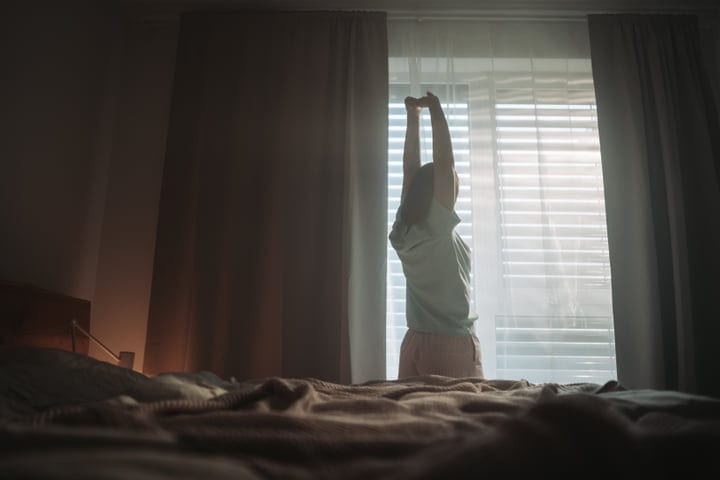 Woman Waking Up And Stretching In A Bedroom With Morning Light