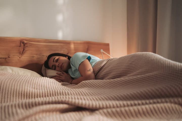Young Woman Sleeping Peacefully In Bed Under A Cozy Blanket