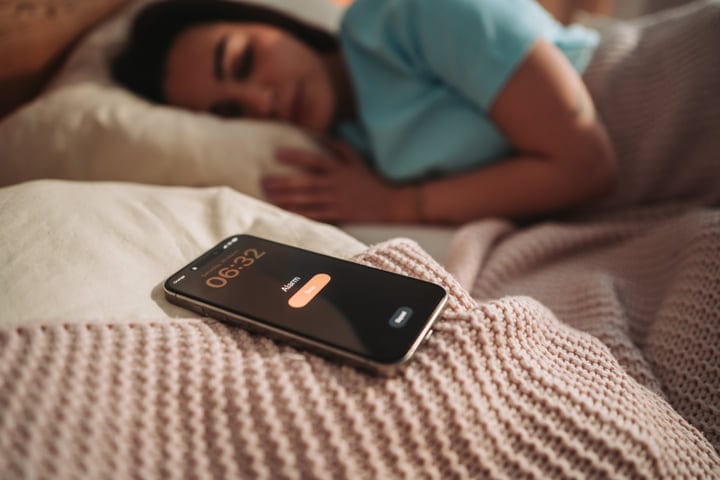 Woman Sleeping Peacefully In Bed With Alarm Clock Set For Early Morning