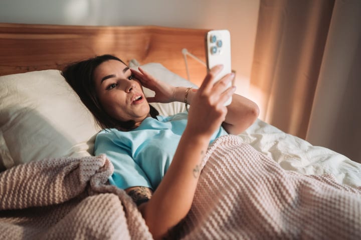 Young European Woman Wakes Up Surprised By Phone In Bed