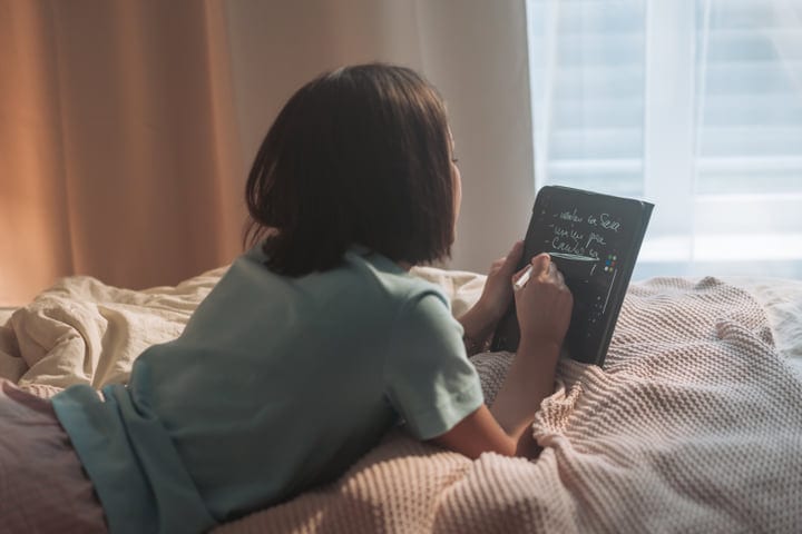 Young Woman Writes In Her Planner On Bed During Morning Routine