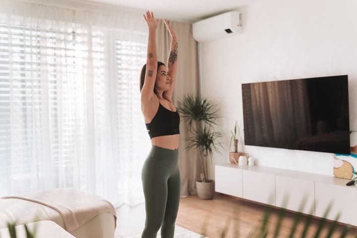 Young Woman Stretching Arms Upwards During Her Morning Routine At Home