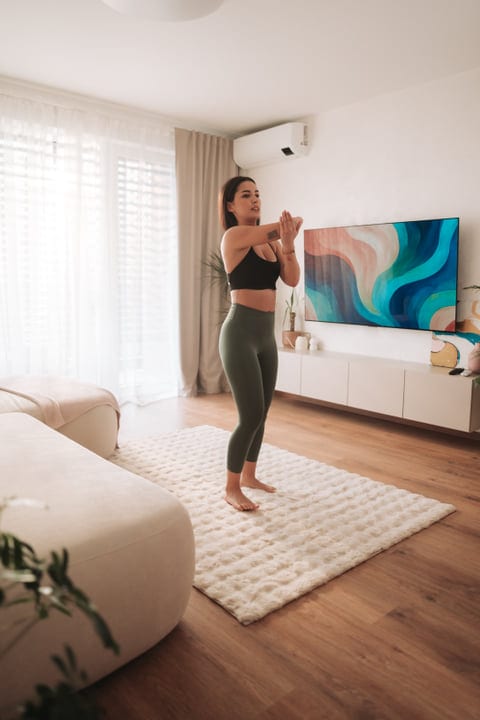 Woman Stretching Arms In Modern Living Room On White Rug