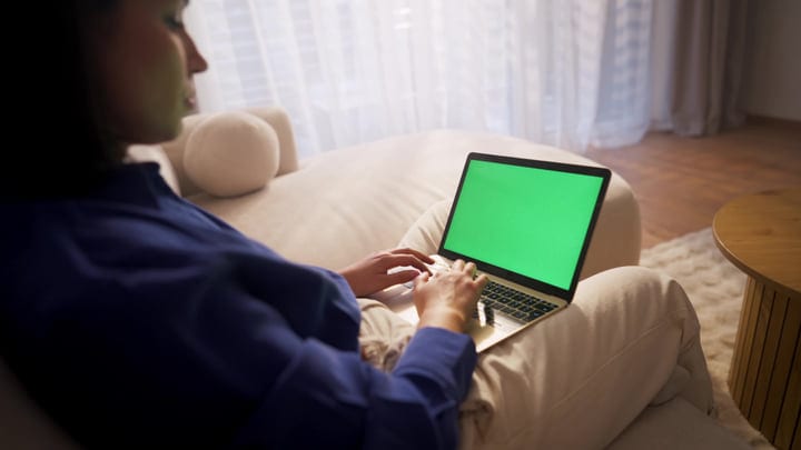 A Young Woman Focuses On Her Laptop From A Bright Home Office Sofa