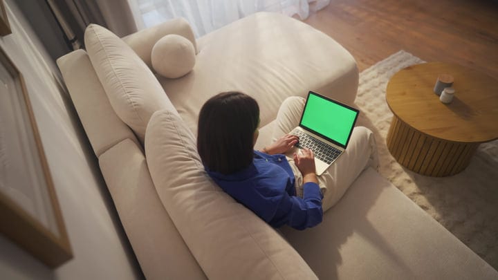 Overhead View Of Woman Using Laptop On Sofa In Cozy Apartment