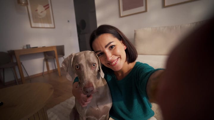 Woman Smiling With Her Dog Taking Selfie In Living Room
