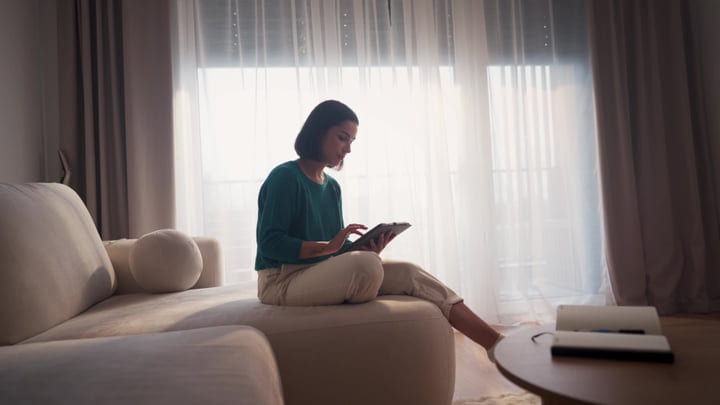 Young Woman Engaged With Tablet On Sofa In Bright Morning Light