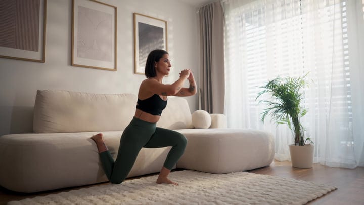 Woman Doing Lunges In Her Bright Modern Living Room At Home