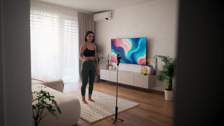 Young Woman Recording Online Fitness Workout In Bright Living Room