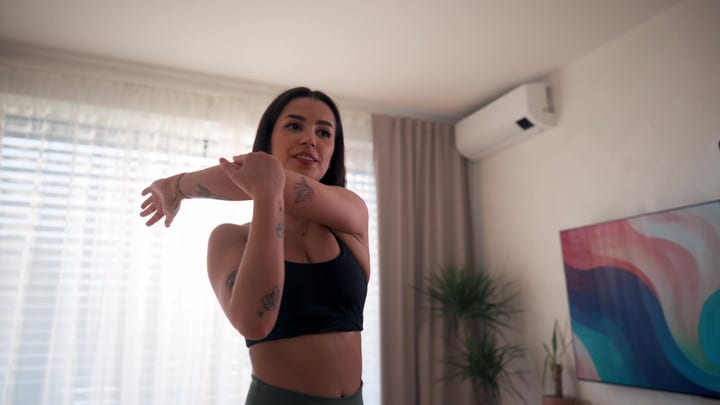 Young Woman With Tattoos Stretches Arm In Her Bright Living Room Morning