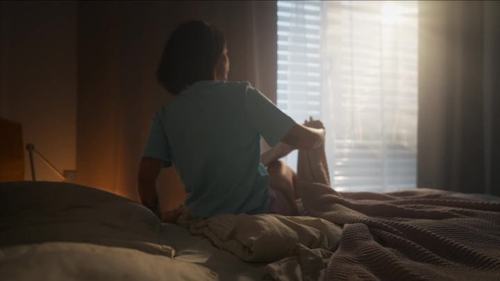 A Woman Stretches In Bed As Morning Light Fills Her Room