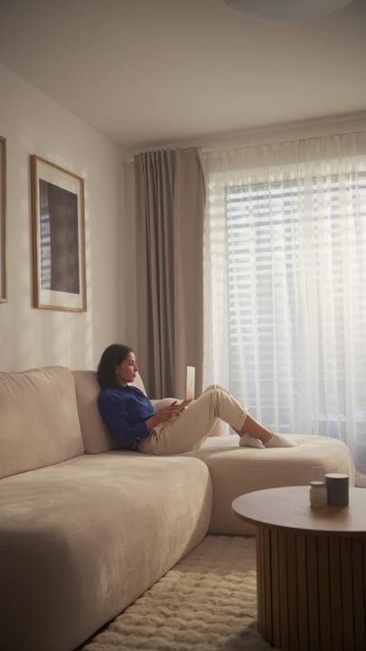 Woman Relaxing On Sofa And Working On Laptop In Bright Living Room