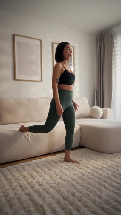 Young Woman Doing Bulgarian Split Squats Using Sofa In Modern Living Room