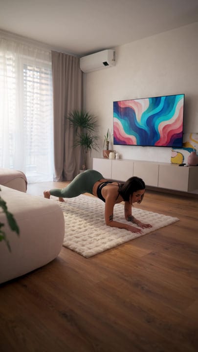 Woman Doing Plank Exercise On Rug In Bright Modern Living Room
