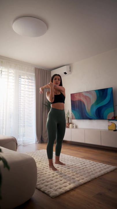 Young European Woman Stretching Her Arm In A Bright Home Living Room