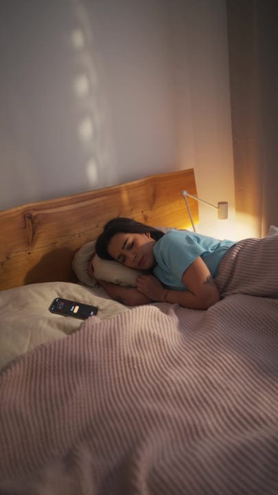 Young Woman Sleeping Peacefully In Her Bed With A Phone Nearby