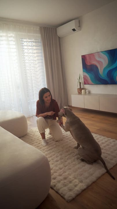 Woman kneeling on rug bonding with dog in morning home light