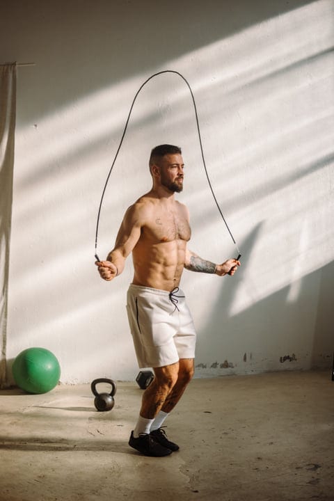 Man With Beard Skipping Rope In Bright Gym With Kettlebell