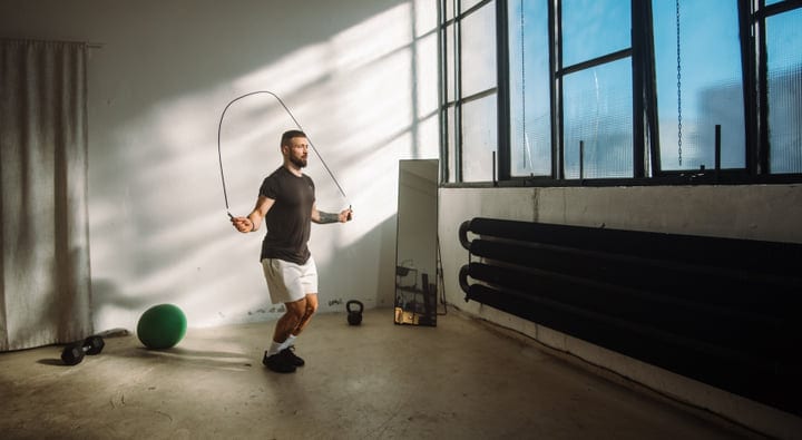 Bearded Man Skipping Rope In A Modern Industrial Gym With Large Windows