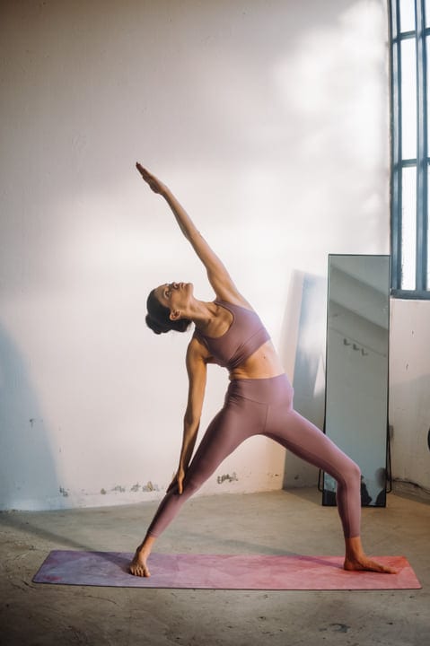 Woman In Pink Activewear Holding Extended Side Angle Yoga Pose On Mat