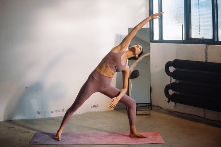 Woman In Mauve Activewear Holding Extended Side Angle Yoga Pose