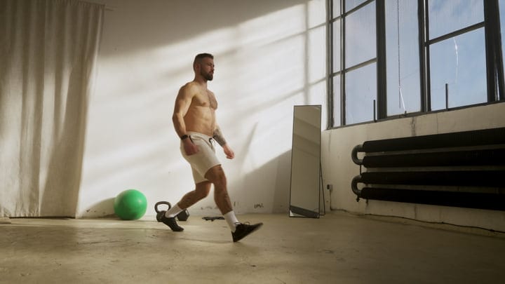 A Muscular Man Performs Lunges In A Bright Industrial-Style Home Gym