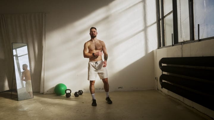Man Practices Yoga In A Bright Studio With Sunbeams And Fitness Gear