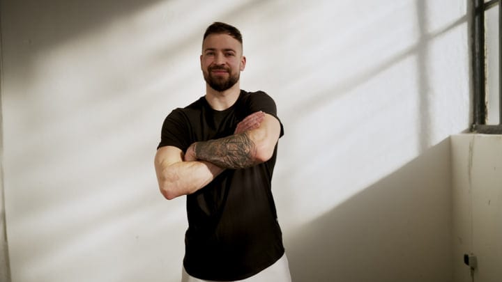 Young Bearded Man Posing With Arms Folded In Minimalist Indoor Studio