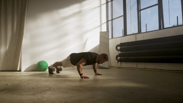 Man Doing Push-Up Exercise On Concrete Floor In Industrial Gym