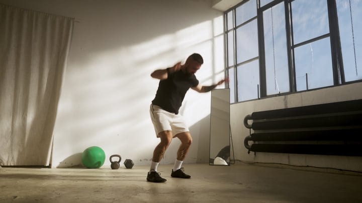 Man Exercising In Bright Studio With Kettlebell And Medicine Ball