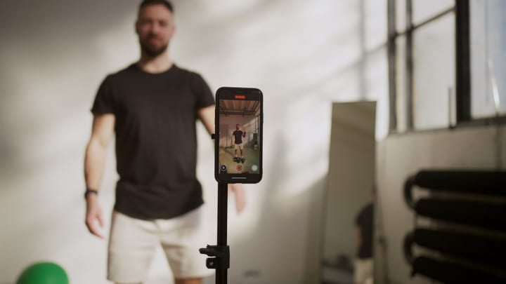 Man Recording His Workout With Smartphone In A Bright Studio.