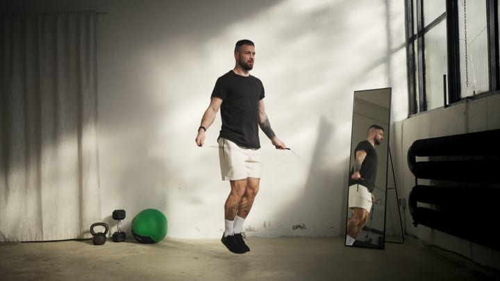 Male Athlete Performing Jump Rope Workout In Concrete Interior Gym