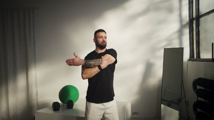 Bearded Man Stretches His Arm During Morning Yoga Session Indoors