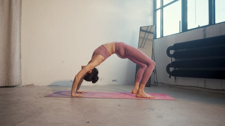 Flexible Woman Holding Urdhva Dhanurasana Pose In Bright Yoga Studio