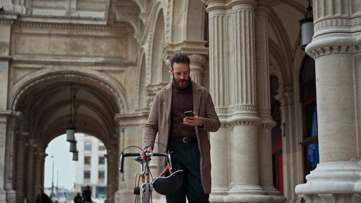 Businessman Navigates City Streets With Smartphone and Bike