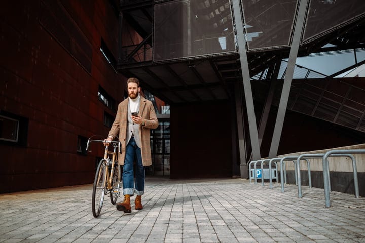 Businessman Strolls with Bicycle on Urban Street