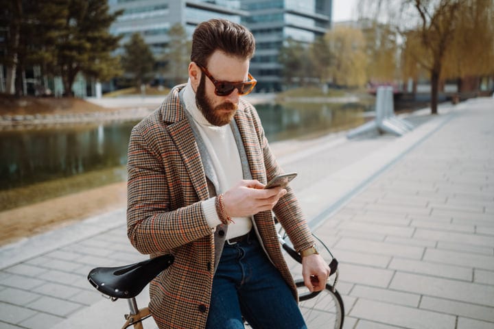 Stylish Businessman Checks Phone During Urban Commute